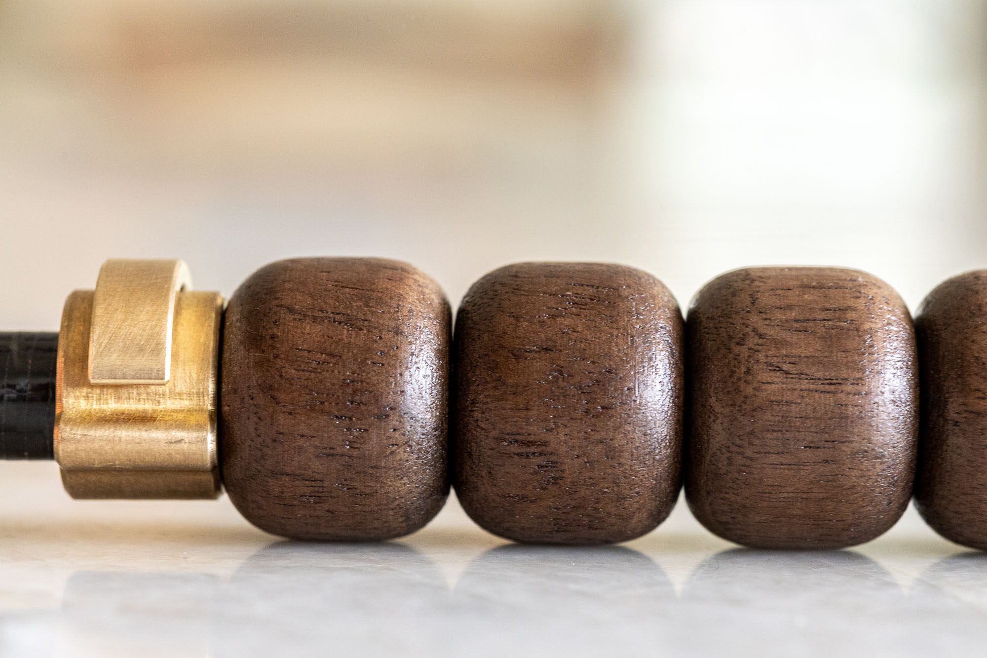 Three smooth hardwood beads beside a brass collar